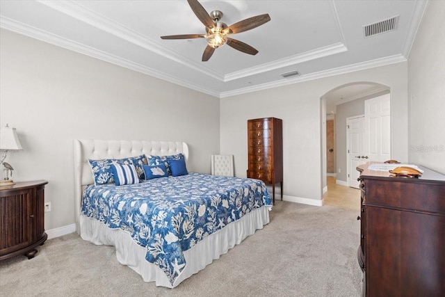 bedroom featuring a tray ceiling, ceiling fan, crown molding, and light carpet