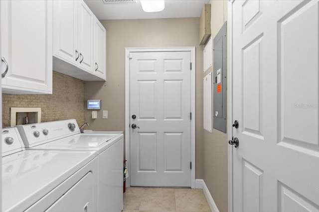 clothes washing area featuring electric panel, cabinets, light tile patterned floors, and washing machine and dryer