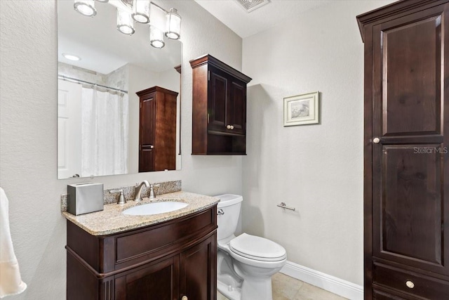 bathroom featuring tile patterned flooring, vanity, toilet, and walk in shower