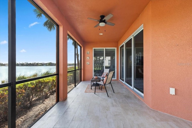 unfurnished sunroom featuring a water view and ceiling fan