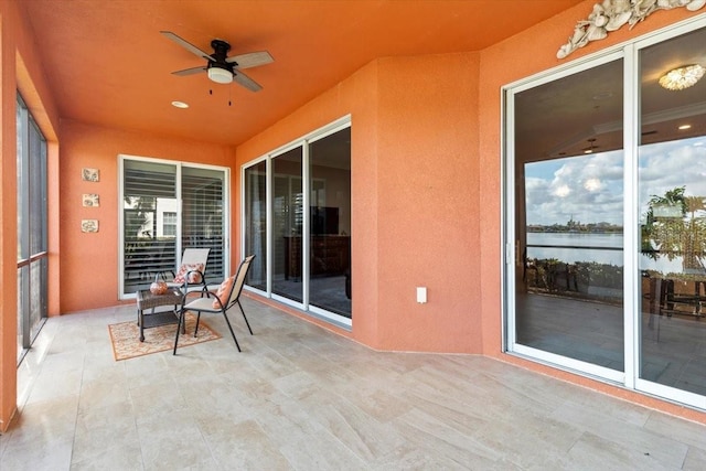 unfurnished sunroom featuring ceiling fan and a water view