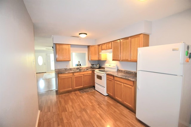 kitchen featuring light wood-type flooring, dark stone counters, white appliances, ceiling fan, and sink