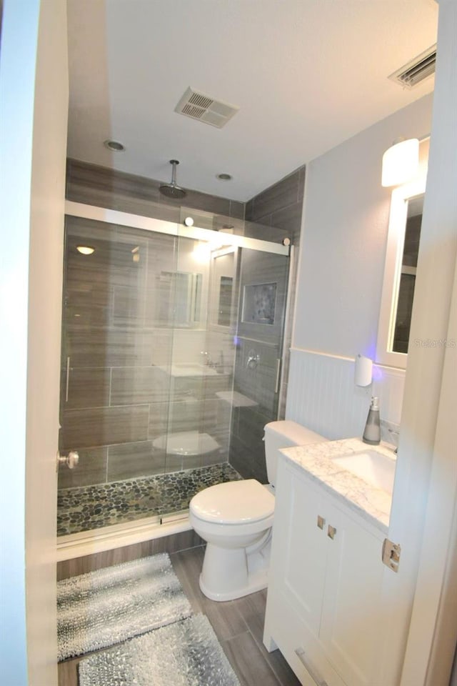 bathroom featuring vanity, hardwood / wood-style flooring, toilet, and a shower with shower door