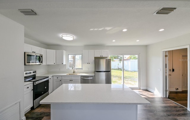 kitchen with stainless steel appliances, a kitchen island, a healthy amount of sunlight, and sink