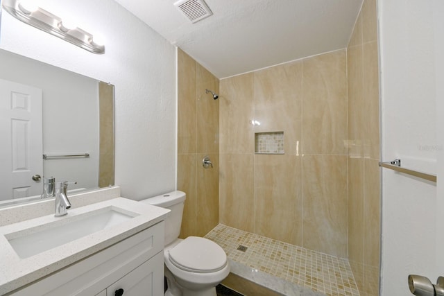 bathroom featuring vanity, toilet, and a tile shower