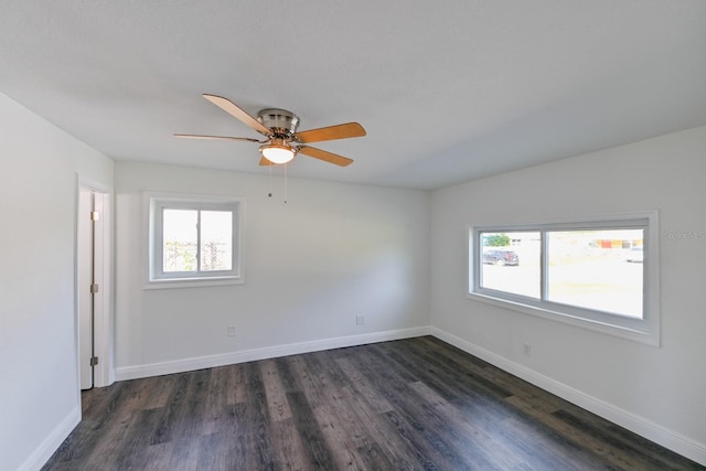 empty room with a wealth of natural light and dark hardwood / wood-style flooring