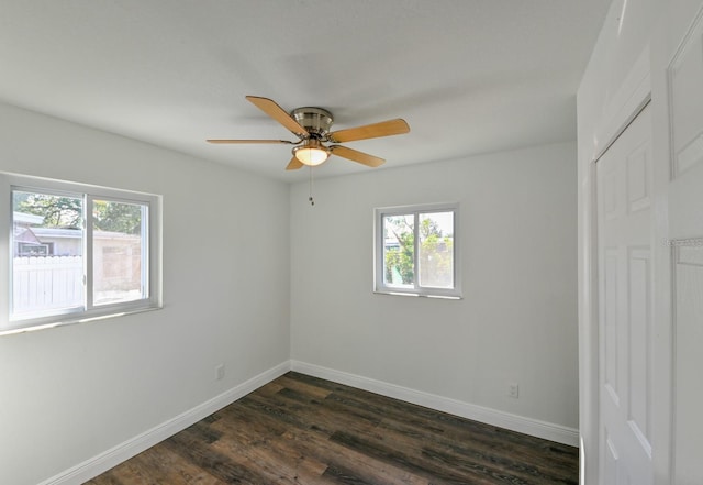 empty room featuring dark hardwood / wood-style floors, ceiling fan, and a wealth of natural light