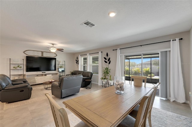 tiled dining area with ceiling fan and a textured ceiling