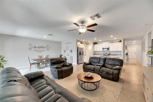 living room featuring a textured ceiling, ceiling fan, and light tile patterned flooring