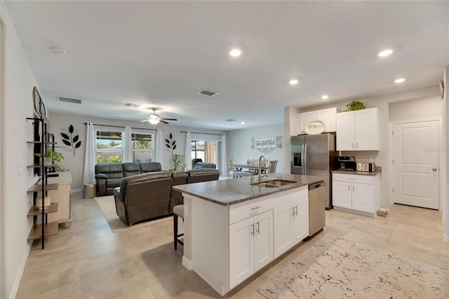 kitchen with white cabinetry, sink, an island with sink, dark stone counters, and appliances with stainless steel finishes