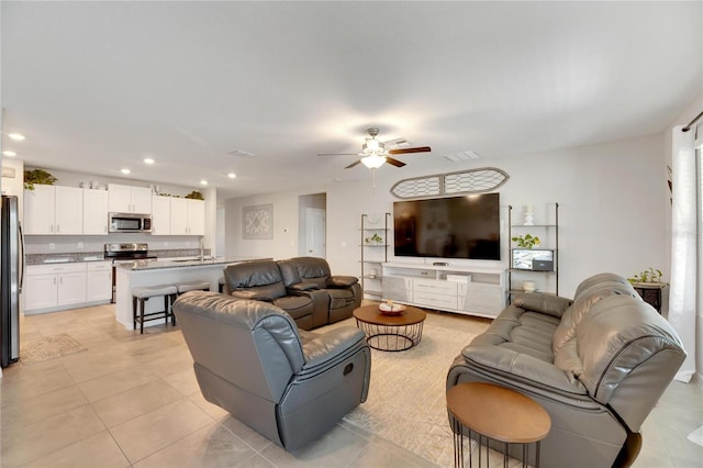 living room featuring ceiling fan, light tile patterned floors, and sink