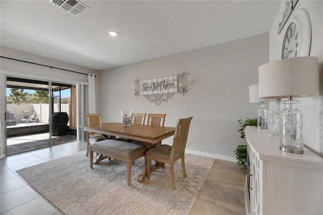 dining space featuring light tile patterned flooring and a textured ceiling