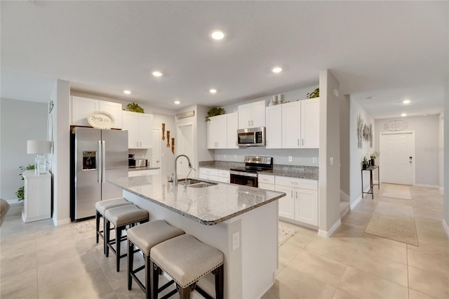 kitchen with appliances with stainless steel finishes, an island with sink, white cabinetry, and sink