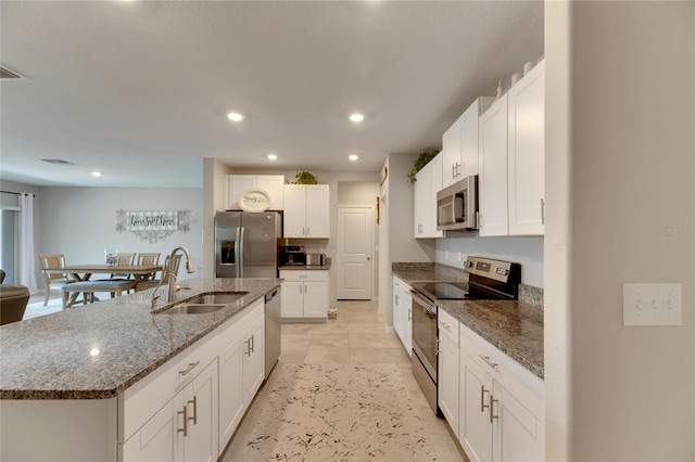 kitchen featuring white cabinetry, sink, appliances with stainless steel finishes, and an island with sink