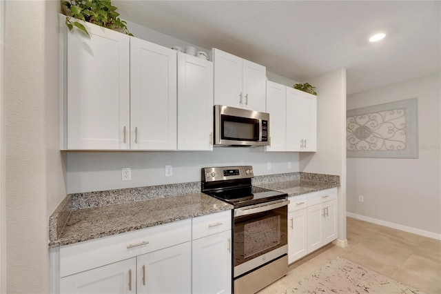 kitchen with light tile patterned floors, light stone counters, white cabinetry, and appliances with stainless steel finishes