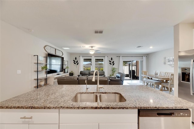 kitchen featuring light stone countertops, stainless steel appliances, ceiling fan, sink, and white cabinetry