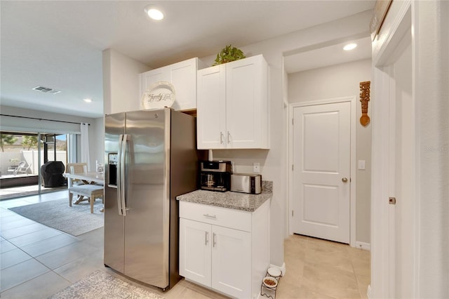 kitchen with white cabinets, light tile patterned flooring, light stone counters, and stainless steel refrigerator with ice dispenser