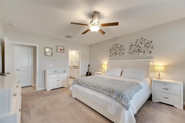 carpeted bedroom featuring ceiling fan and ensuite bath