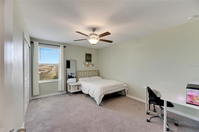 bedroom featuring ceiling fan, light colored carpet, and a textured ceiling