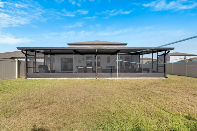 rear view of house featuring a lawn and a sunroom