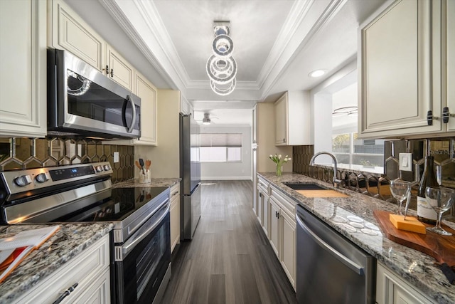 kitchen featuring sink, stainless steel appliances, light stone counters, dark hardwood / wood-style floors, and a tray ceiling