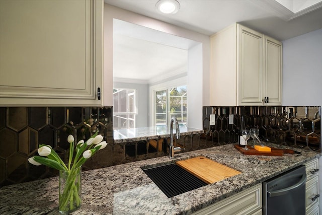 kitchen with tasteful backsplash, sink, cream cabinets, stone counters, and dishwasher