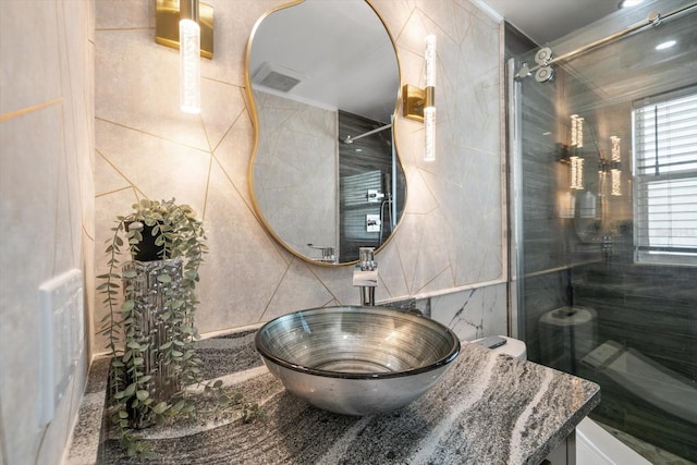 bathroom with tiled shower, tile walls, and vanity