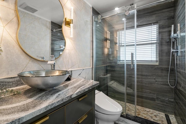 bathroom with an enclosed shower, vanity, toilet, and tile walls