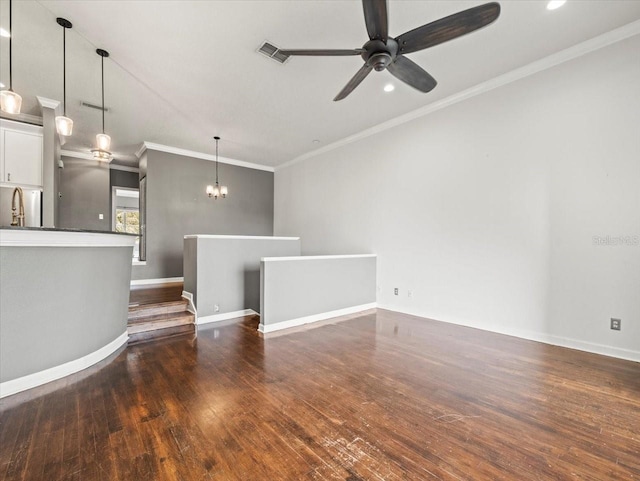 unfurnished living room with ceiling fan with notable chandelier, dark hardwood / wood-style flooring, and ornamental molding