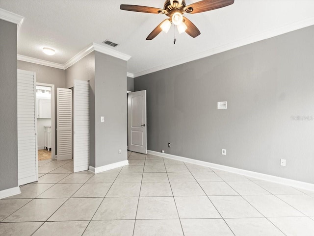 unfurnished bedroom with ceiling fan, a walk in closet, ornamental molding, and light tile patterned floors