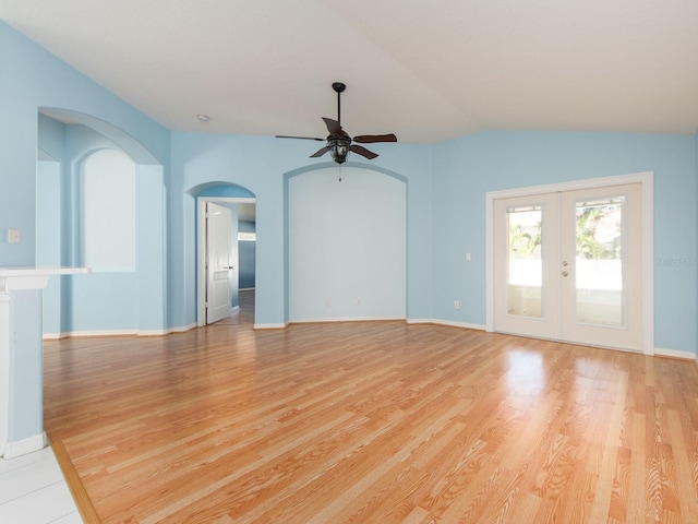 unfurnished living room featuring ceiling fan, french doors, light hardwood / wood-style floors, and vaulted ceiling