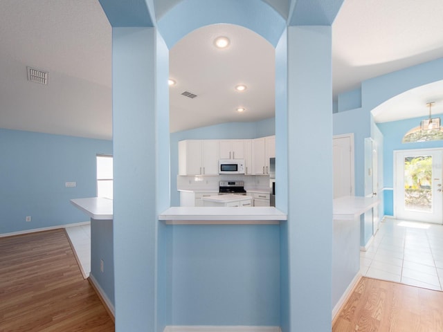 kitchen with white cabinets, light hardwood / wood-style floors, kitchen peninsula, and stainless steel range with electric stovetop