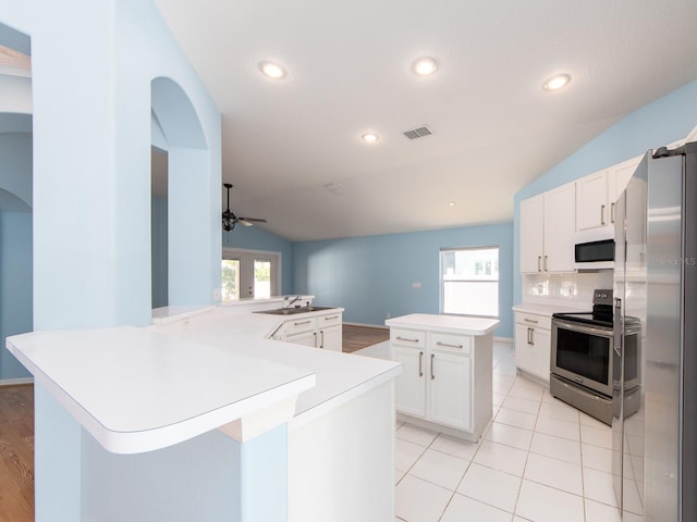 kitchen featuring white cabinetry, ceiling fan, kitchen peninsula, lofted ceiling, and appliances with stainless steel finishes