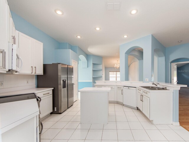 kitchen featuring white cabinetry, a center island, sink, kitchen peninsula, and white appliances