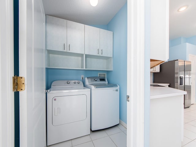 washroom featuring cabinets, light tile patterned flooring, washer and dryer, and a textured ceiling