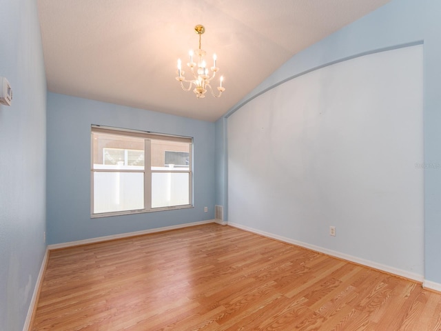 empty room featuring light wood-type flooring, vaulted ceiling, and a notable chandelier