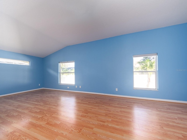 spare room with light wood-type flooring and lofted ceiling