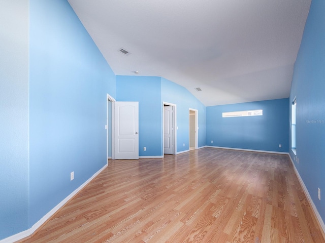 spare room featuring lofted ceiling and light hardwood / wood-style flooring