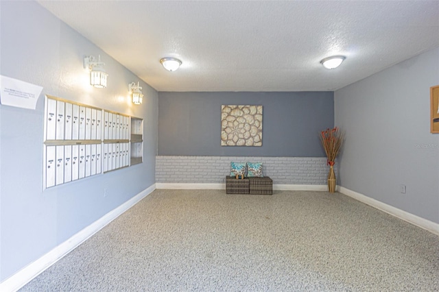 interior space with carpet flooring, mail boxes, brick wall, and a textured ceiling