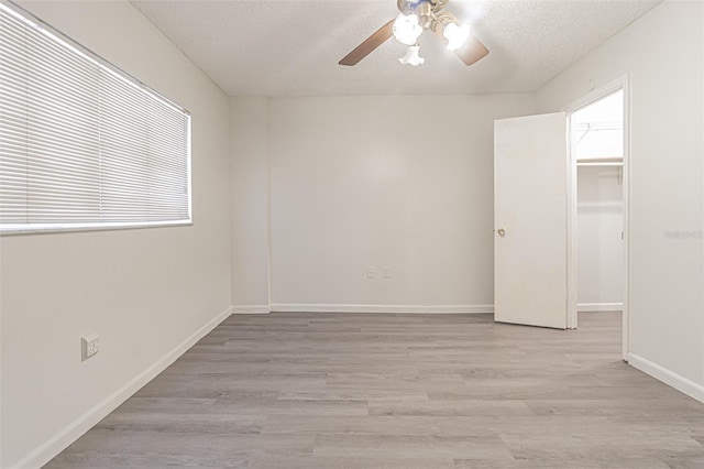 spare room with a textured ceiling, light wood-type flooring, and ceiling fan