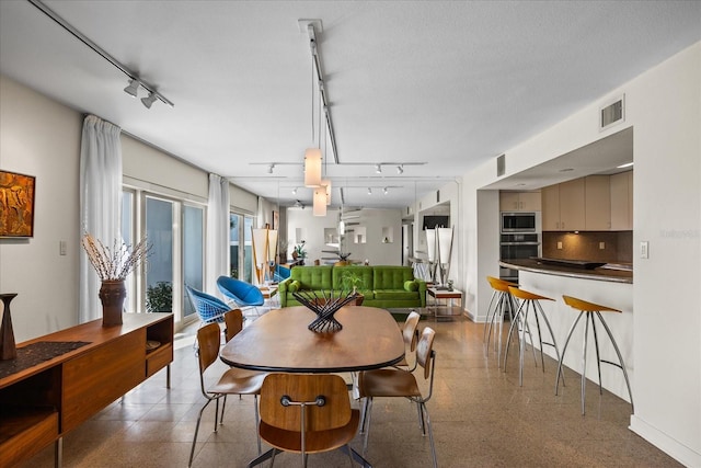 dining area featuring rail lighting and a textured ceiling