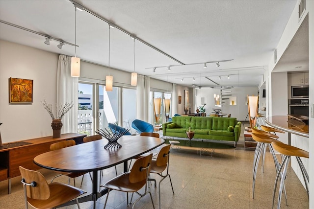 dining room with a textured ceiling and rail lighting