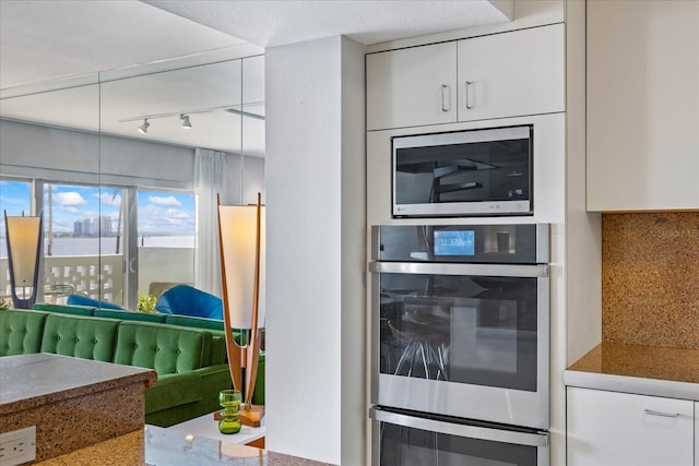 kitchen with white cabinets, stainless steel appliances, and tasteful backsplash