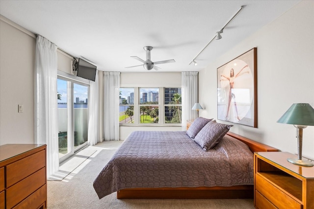 bedroom with light carpet, rail lighting, access to outside, and ceiling fan