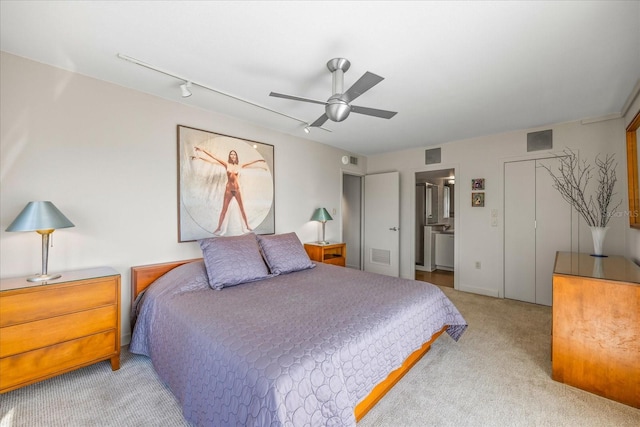 carpeted bedroom with rail lighting, ensuite bath, and ceiling fan