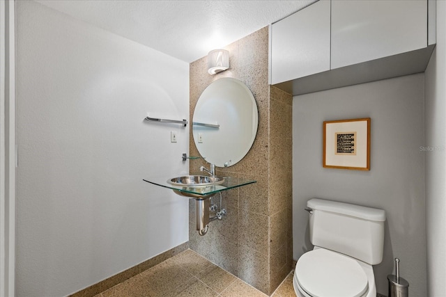 bathroom with sink, tile walls, and toilet