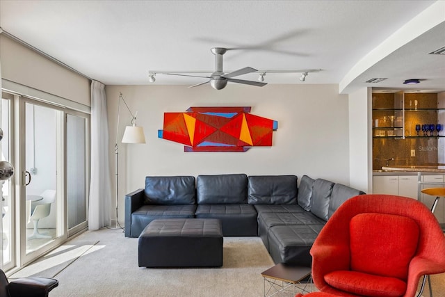 living room featuring ceiling fan, light colored carpet, and track lighting