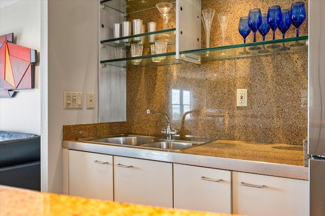 bar with backsplash, sink, and white cabinets