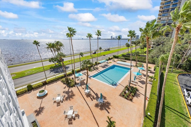 view of pool featuring a yard, a water view, and a patio area