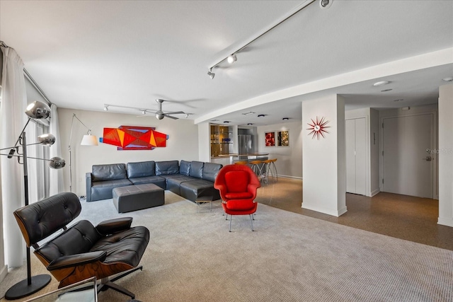 living area featuring rail lighting, a ceiling fan, and baseboards